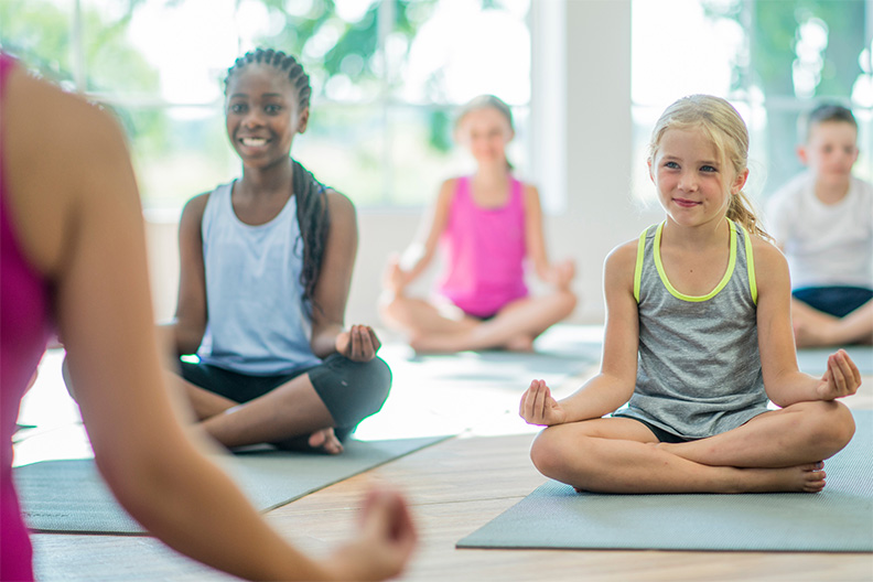 children practising wellbeing and yoga