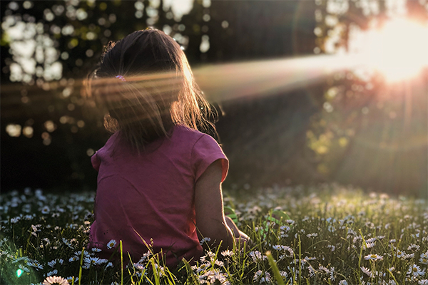 child sat outside in late summer sun