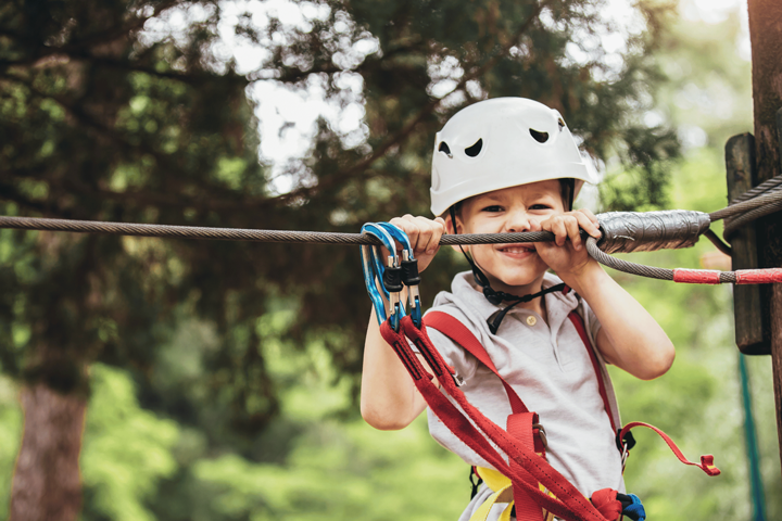child in harness on high ropes course